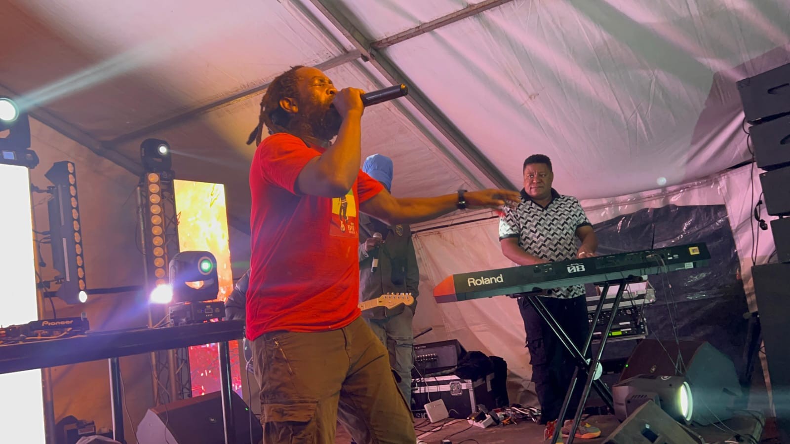 A vocalist performing alongside a keyboard player inside a festival tent