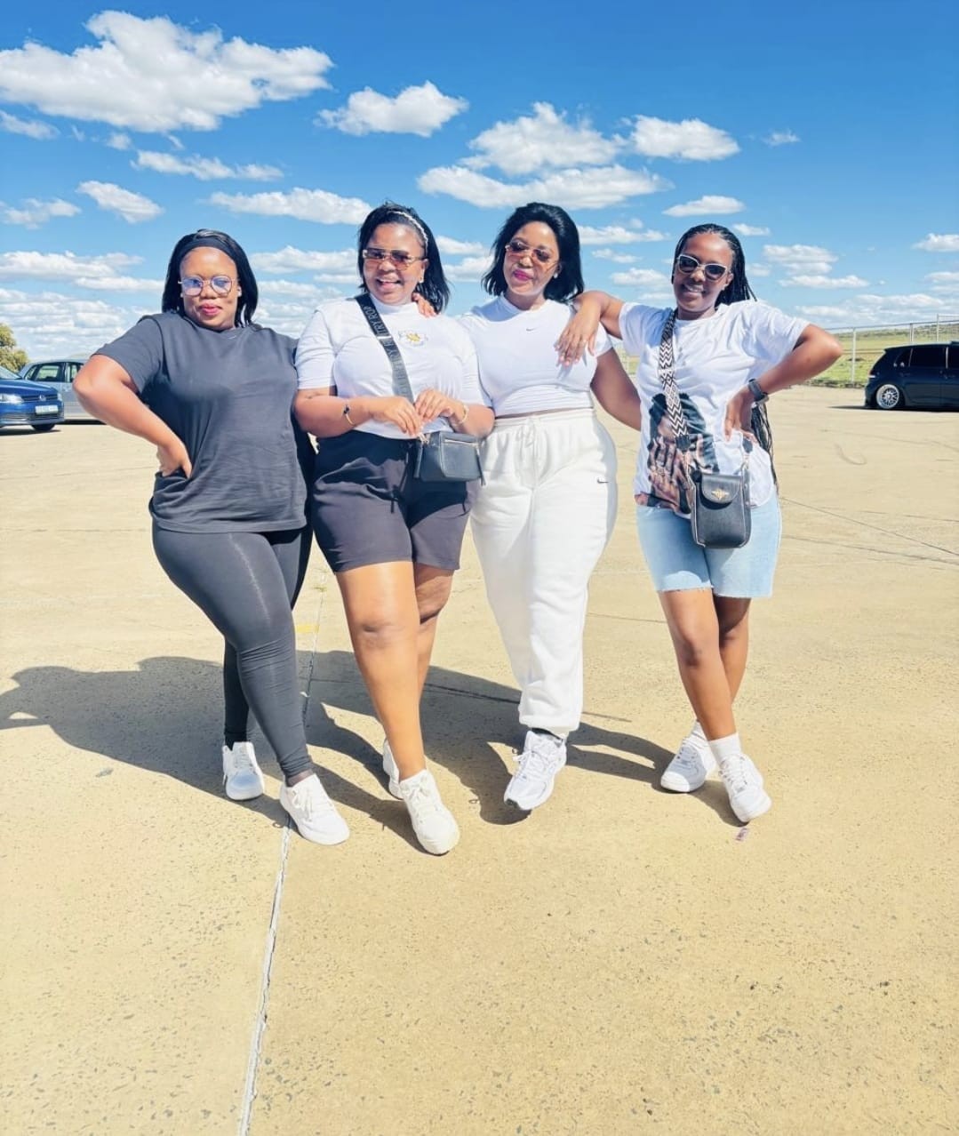Four friends smiling together outdoors on a sunny day