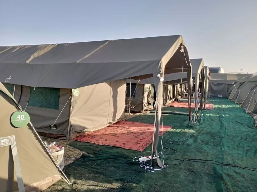 Furnished glamping tents with covered entrances set up along a campsite walkway