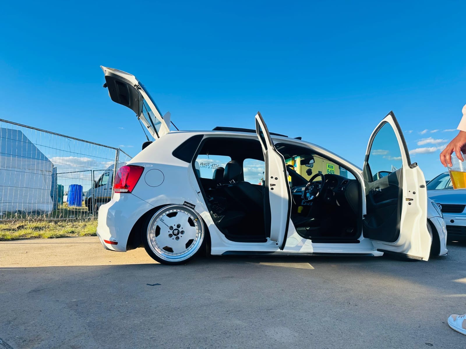 A white modified car with doors and boot open at a car show