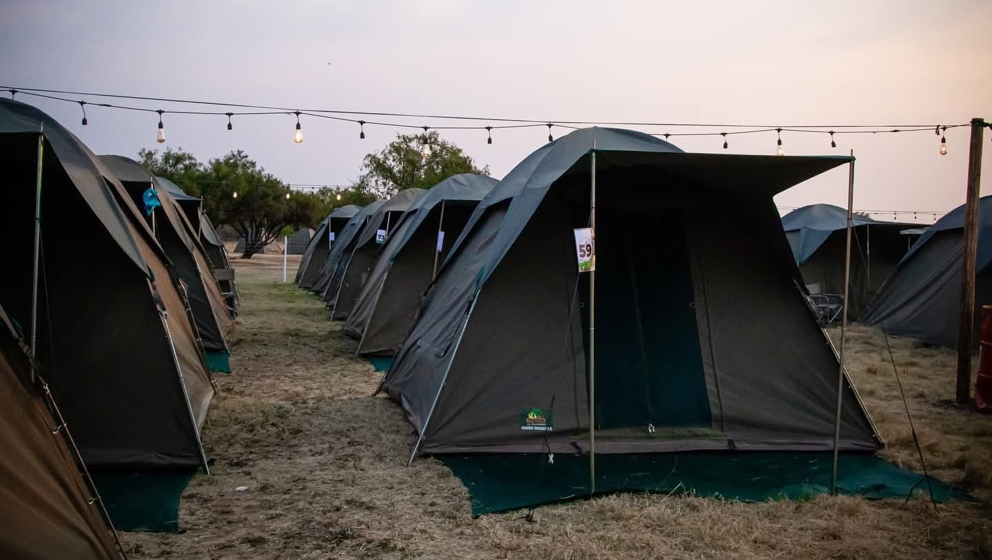 A row of canvas tents under a blue sky